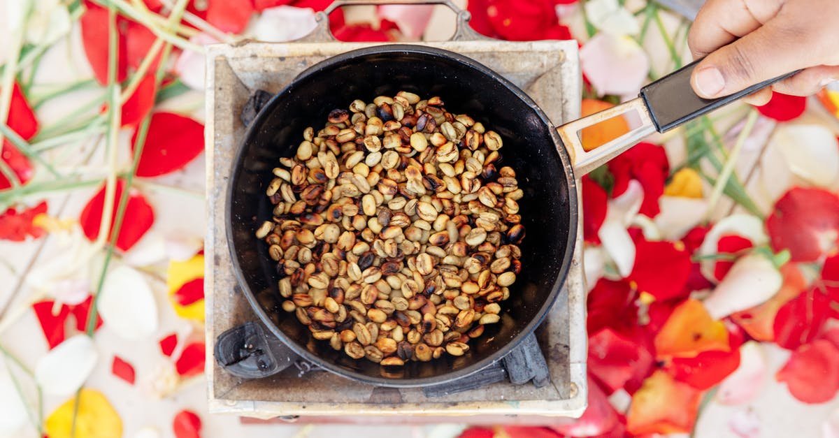 Baking in gas oven does not brown the top - Top view of crop unrecognizable cook frying halved brown and golden crunchy peanuts on old portable gas stove while holding handle of frying pan above colorful oilcloth on table