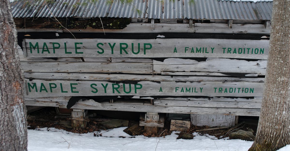 Baking maple syrup on cold smoked almonds - Shabby wooden construction with inscription Maple Syrup located between trees in snowy countryside