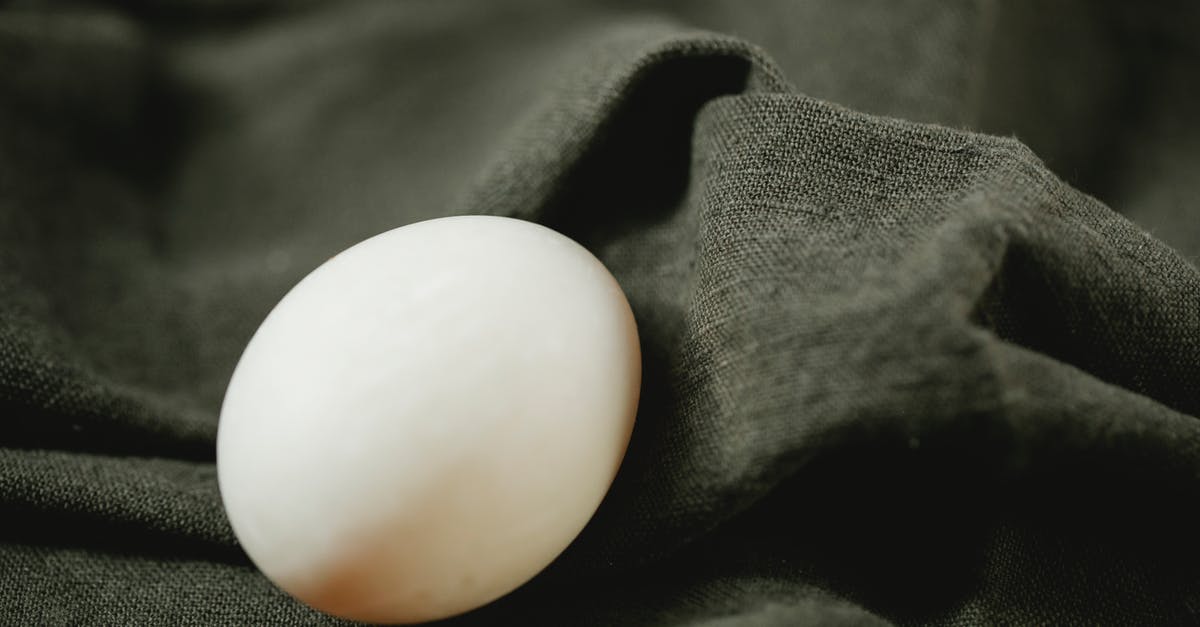 Baking Soft Boiled Eggs? - Composition of organic white chicken egg placed on black soft textile in bright light