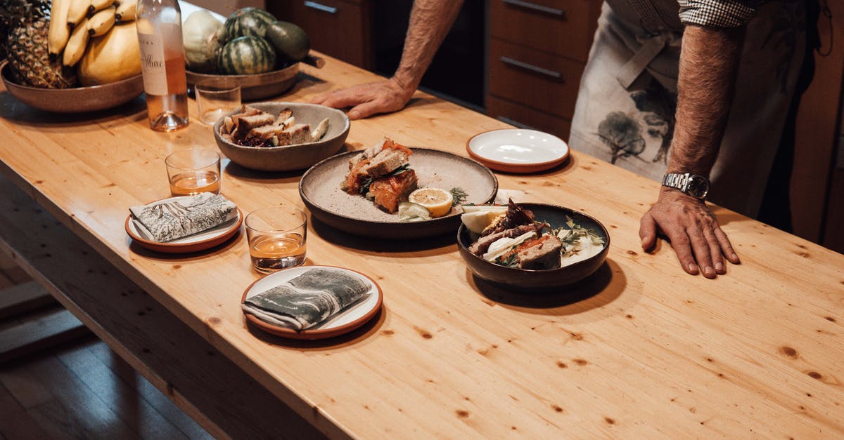 Baking watermelon - Crop unrecognizable male leaning on wooden desk with delicious appetizers and fresh fruits against alcoholic drink in glasses at home