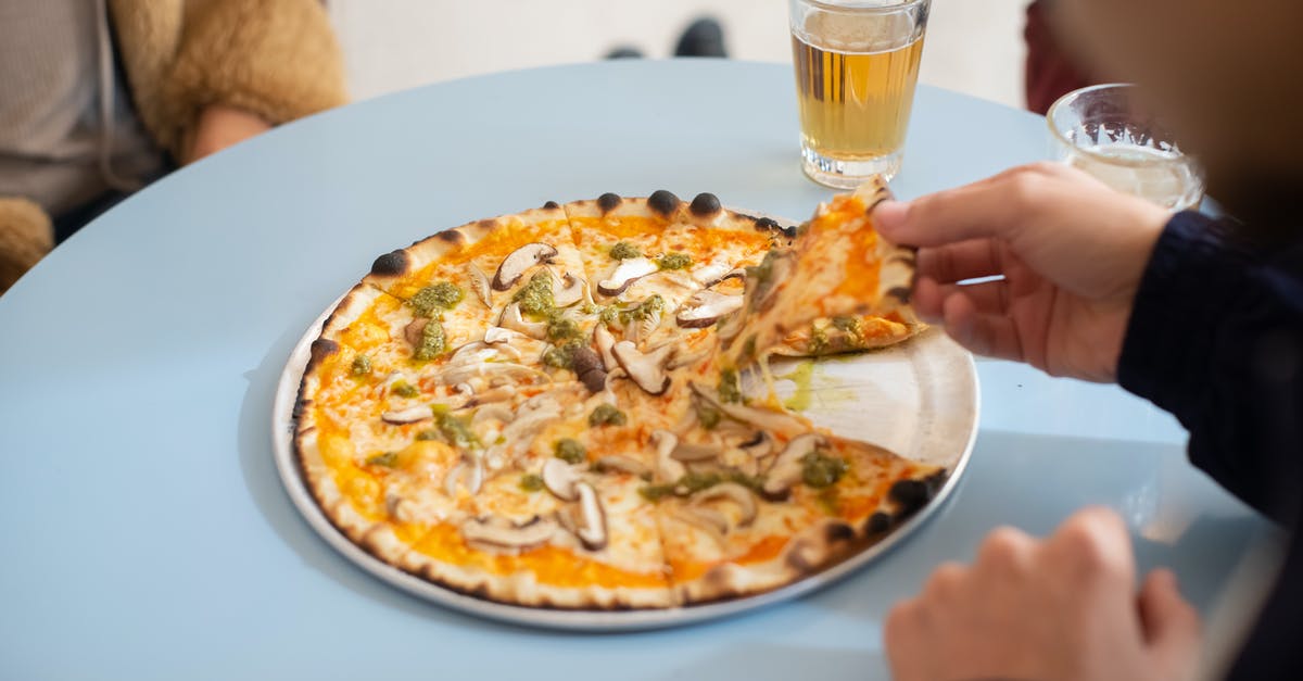 Balancing out a good souffle and burnt cheese on top - A Person in Black Long Sleeve Shirt Holding a Slice of Pizza on a Round Tray