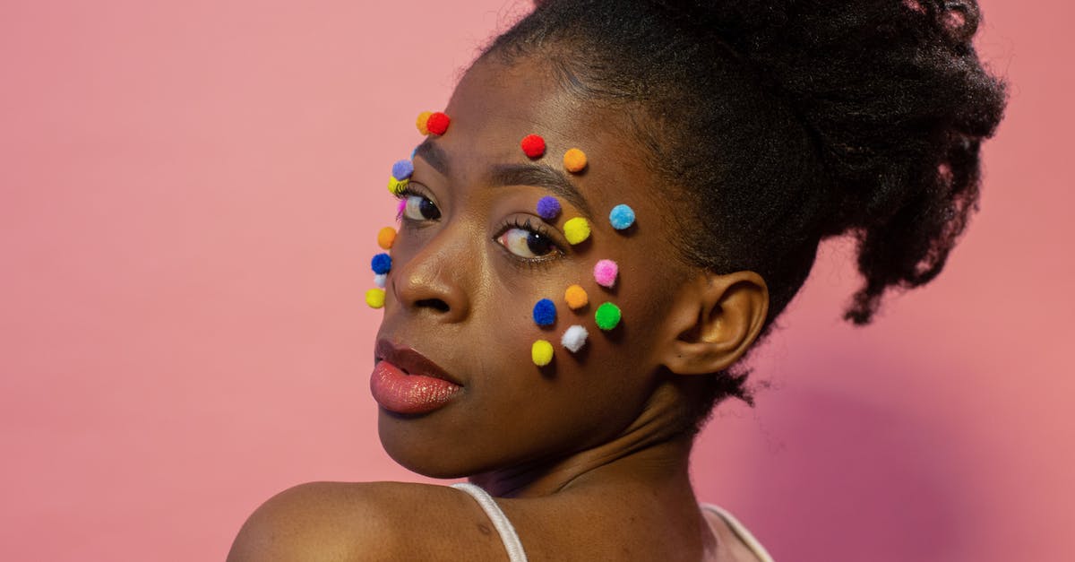 Ball Canning Jars: Use them over and over? - Confident young black woman with multicolored fluffy small balls on face looking over shoulder in bight studio on pink background