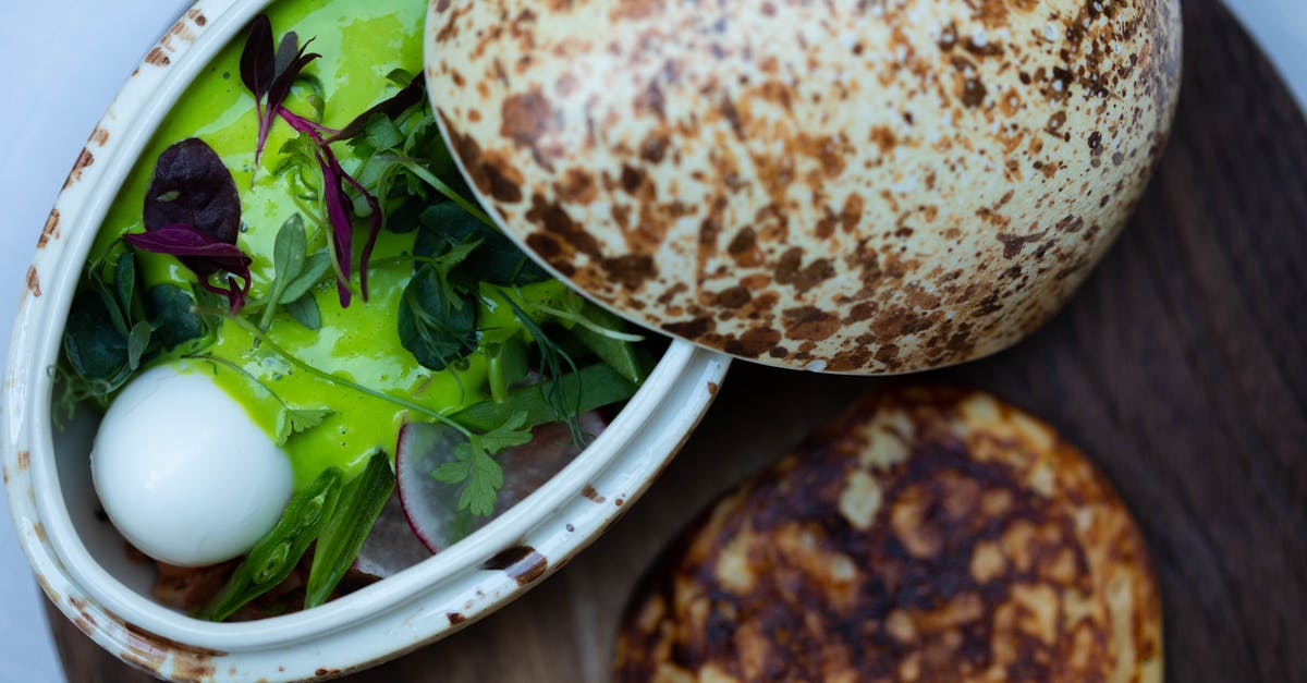 Basil Pesto and Cream Cheese dip - From above of appetizing vegetable and greenery and cheese salad with pesto sauce in pottery with open lid served with flatbread on wooden board