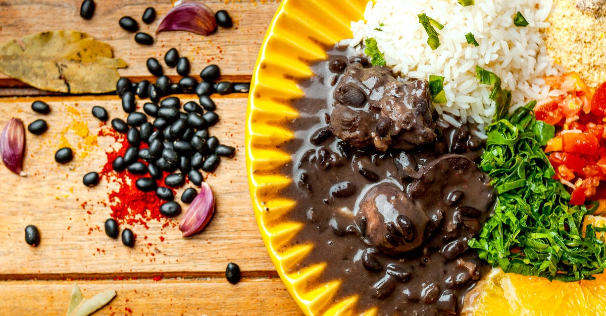 Bean based stew. Alternative to tomatoe sauce - Top view arrangement of tasty black bean stew served on yellow plate with rice and couscous topped with cut tomatoes and parsley