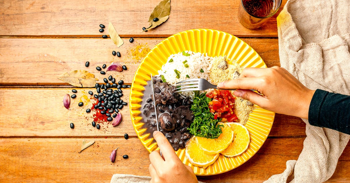 Bean based stew. Alternative to tomatoe sauce - Top view crop anonymous person with cutlery enjoying yummy black bean stew served with rice and couscous topped with parsley and cut tomatoes