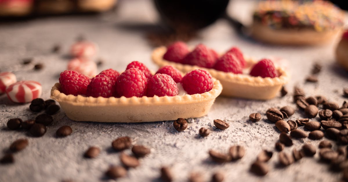 Bean selection for a chili recipe - Delicious fresh raspberry tartlets placed on table amidst aromatic coffee beans and sweets