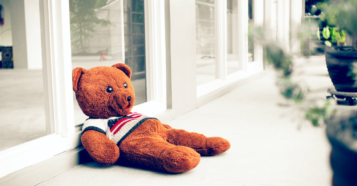 Bear in a crock pot - Toy bear on walkway against glass wall