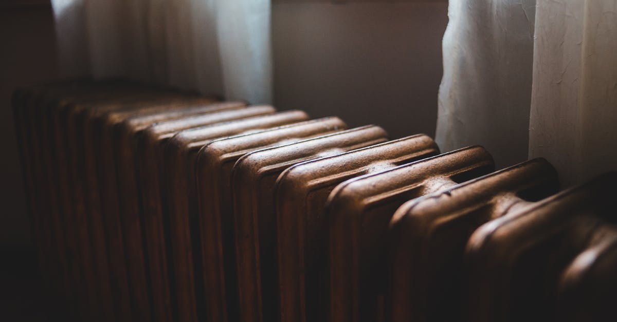 Benefits of a cleaned/seasoned cast iron - Aged heating battery made of cast iron near windowsill with curtains in house