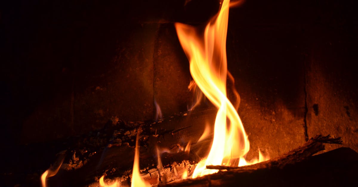 Best method to determine temperature while heating sugar - Burning firewood with bright orange flames in fireplace in dark room at night