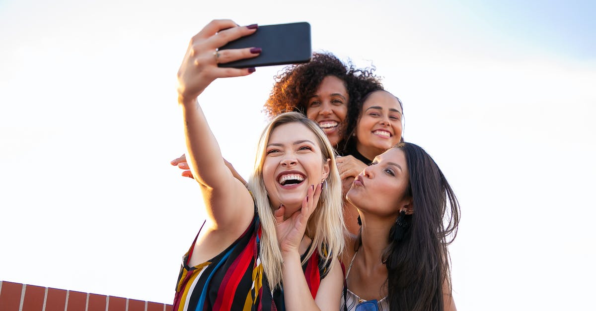 Best moment to put salt in spaghetti? - Cheerful multiethnic girlfriends taking selfie on smartphone on sunny day