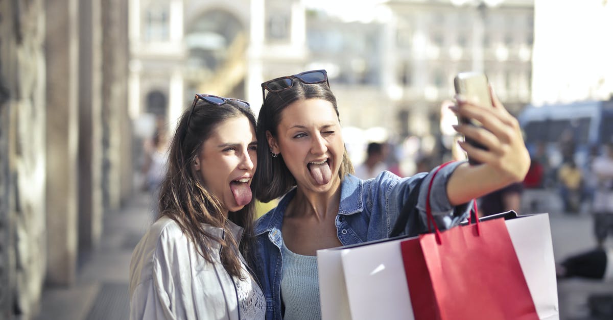 Best moment to put salt in spaghetti? - Cheerful young women with shopping bags taking selfie on street