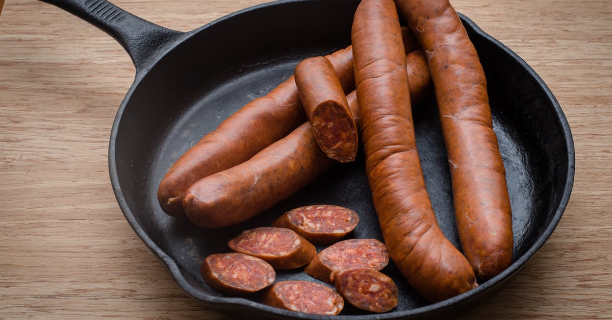 Best practices to minimize smoke when cooking meat using a cast iron skillet - Tasty sausages in frying pan on table Best practices to minimize smoke when cooking meat using a cast iron skillet - Tasty sausages in frying pan on table