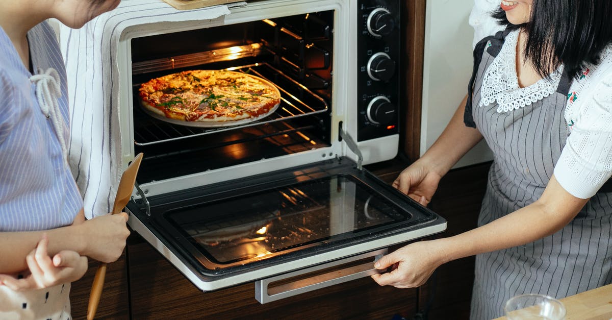 Best thickness for shaped pizza dough for good sliding from the peel/tray into the oven - Crop women putting pizza in oven