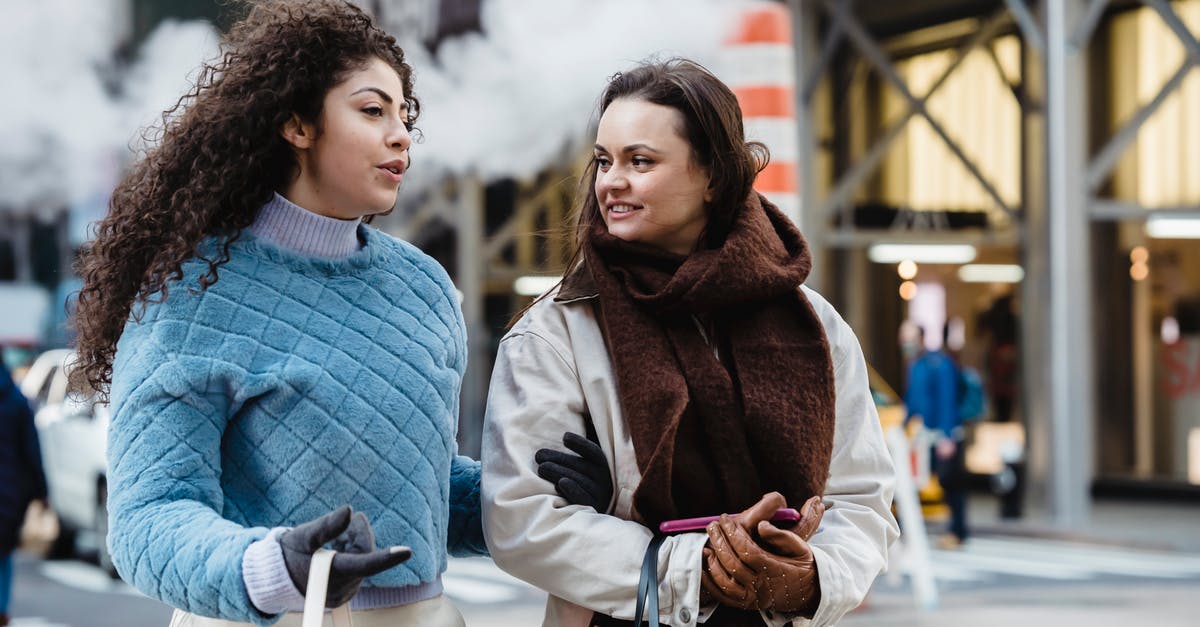 Best way to cheat at hollandaise? - Positive stylish multiethnic women talking and crossing road in city