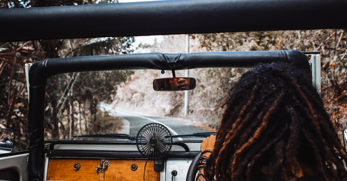 Best way to cheat at hollandaise? - Back view of unrecognizable traveler with stylish dreadlocks spinning steering wheel while driving car and reflecting in small mirror