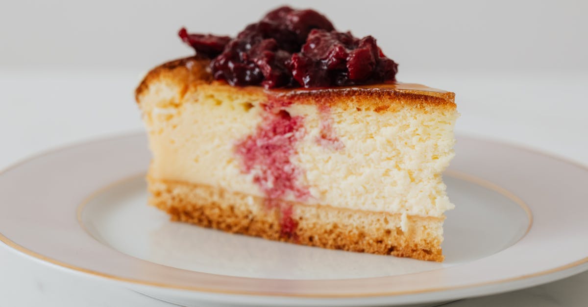 Best way to cut up a cheesecake into bites - Closeup of piece of yummy homemade cheesecake with berries in syrup on top served on plate