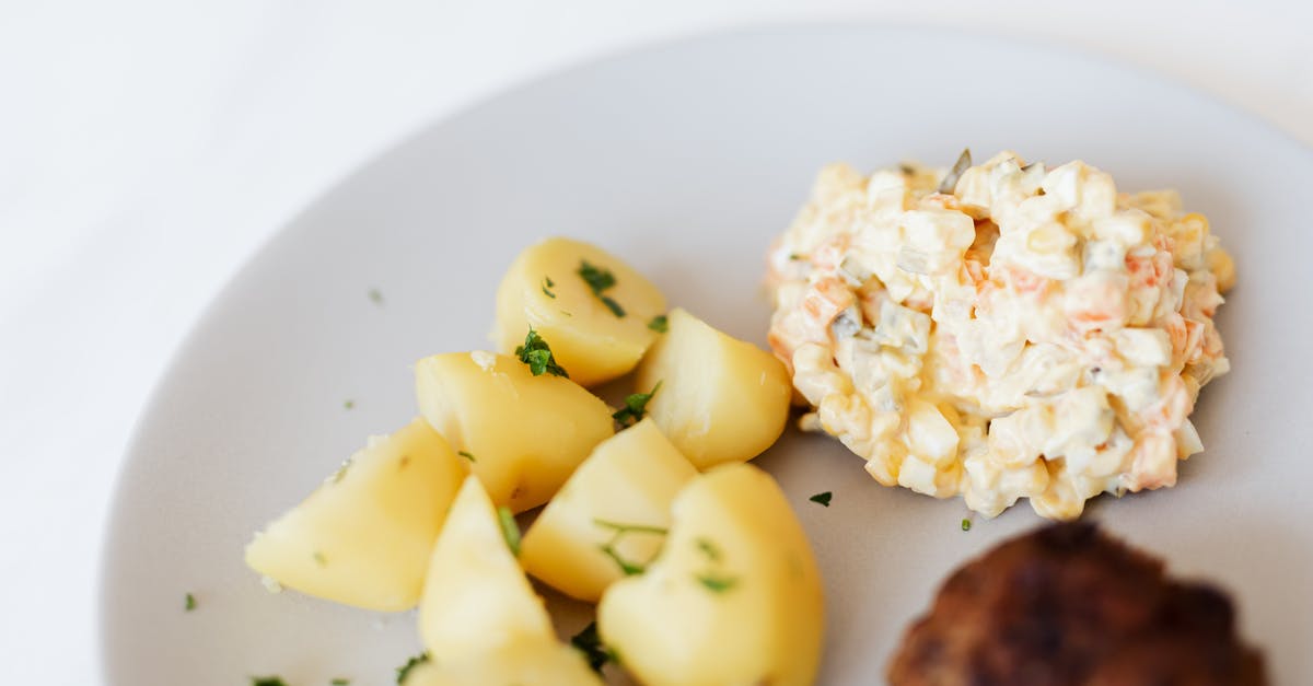 best way to infuse flavour into boiled potatoes - From above of plate with juicy fried meat cutlet served with delicious Russian meat salad and boiled potatoes topped with parsley placed on white table