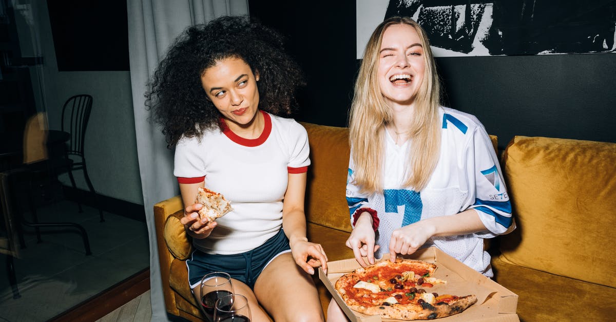 Best way to reheat pizza - Two Young Women Eating and Getting a Slice of Pizza