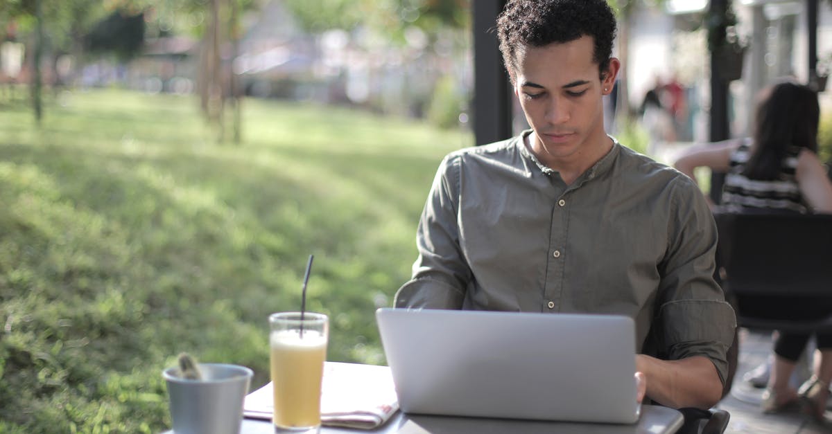 black residue in tea kettle - Focused black male freelancer using laptop in street cafe