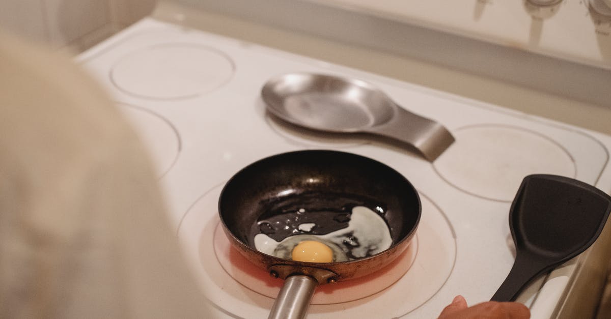 Black residue inside frying pan - Crop person cooking fried eggs