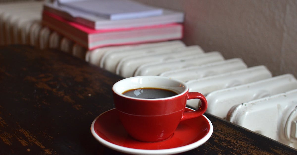 Black spots in porcelain coffee mug - Cup of coffee on table near radiator