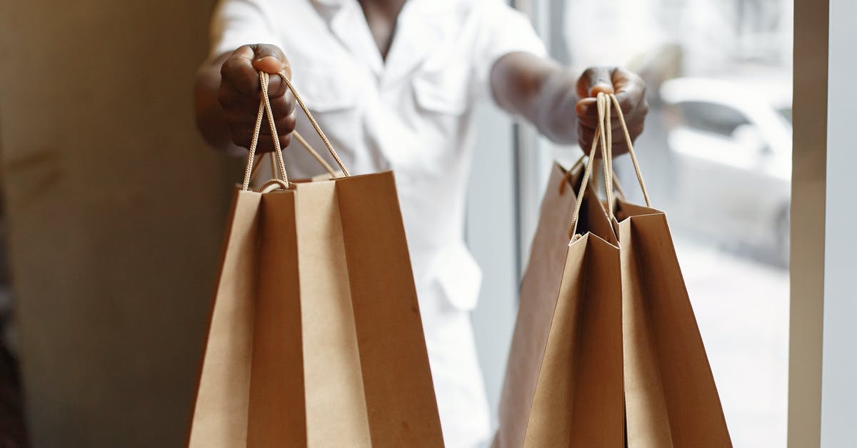 Black spots while ripening store brought mangoes by paper [duplicate] - Crop anonymous African American person in white jacket passing purchases in paper shopping bags while standing near window in daylight