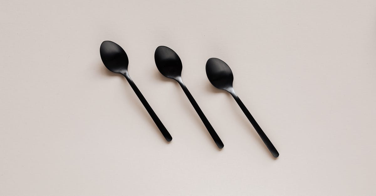 Black spotting/dust in stainless steel utensils.Is this mildew? - Set of shiny black spoons on gray table