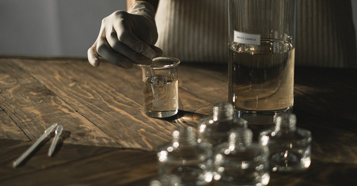 Blender makes burning smell after liquid spilled on (maybe into) it - Crop anonymous female in latex gloves making fluid for perfume among glass jars on wooden table