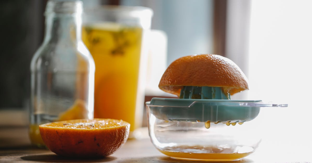 Blender vs food processor vs juicer - Half of delicious sweet orange placed on plastic orange juicer placed on kitchen table