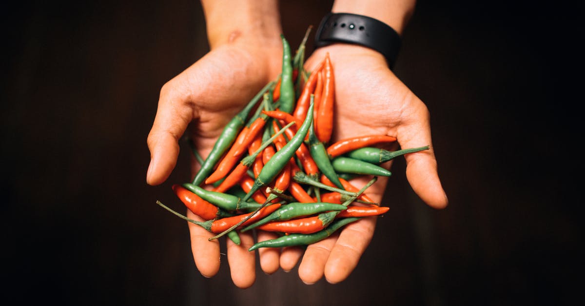 Blue floaters in canned hot peppers - Person Holding Green and Red Chili Peppers