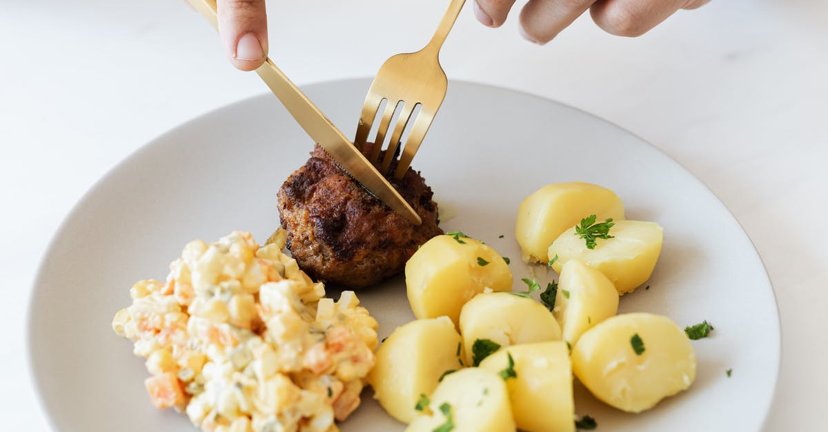 Boiled chicken: coloured parts of the meat? - From above of crop anonymous person cutting with cutleries fried juicy meat cutlet served on white plate with tasty boiled potatoes and Russian salad