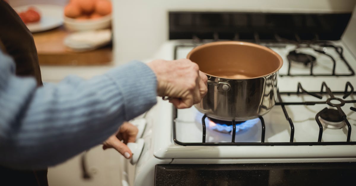 Boiled water left in a Teflon pot - Crop unrecognizable housewife placing saucepan on burning stove