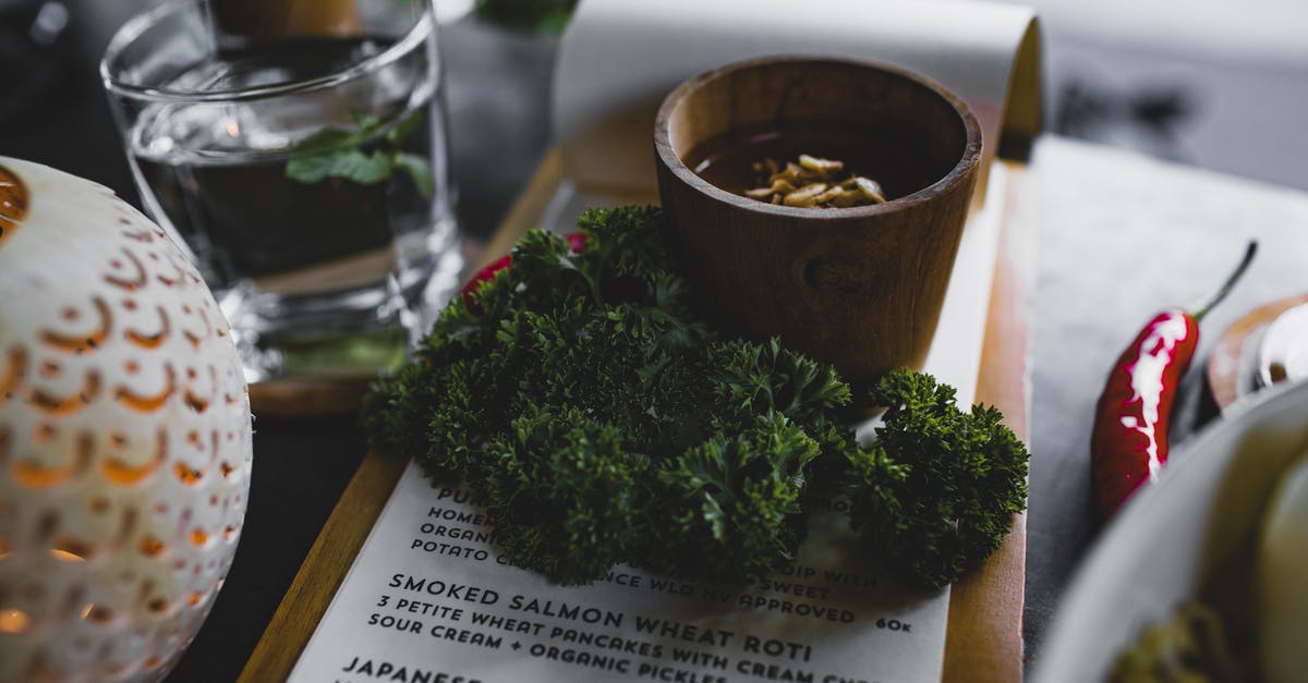 Books for very high level vegan cooking? - High angle table with bunch of fresh green curly parsley placed on menu with sauce cup near glass of water