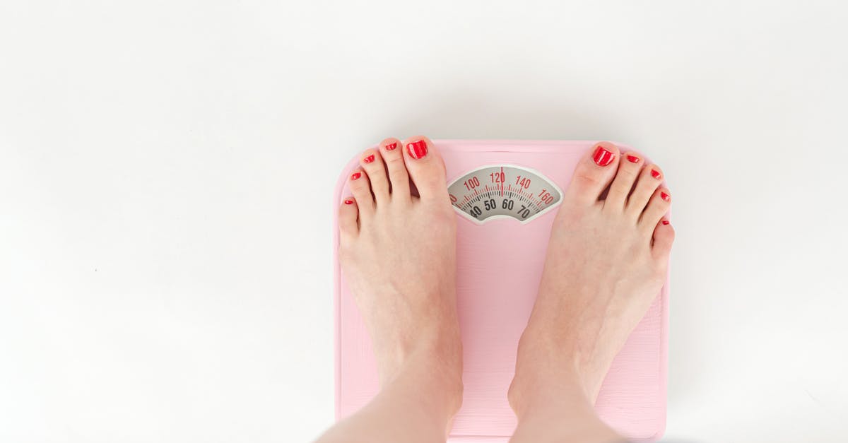 Both over- and undercooked beans from a pressure cooker - Top view of crop anonymous barefoot female measuring weight on scales on white background