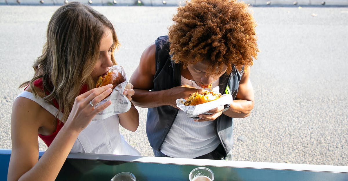 Bread going stale in enamel breadbasket - Multiethnic couple biting hamburgers during lunch together