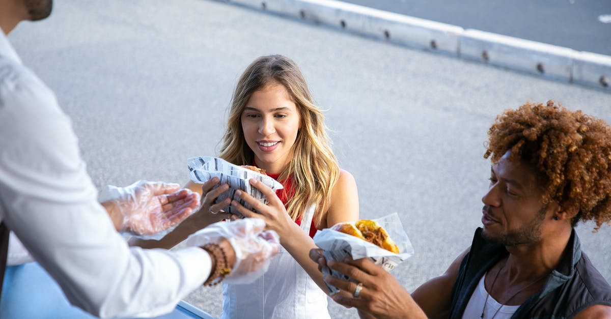 Bread going stale in enamel breadbasket - High angle of positive multiracial couple getting delicious burgers from salesman working in food truck