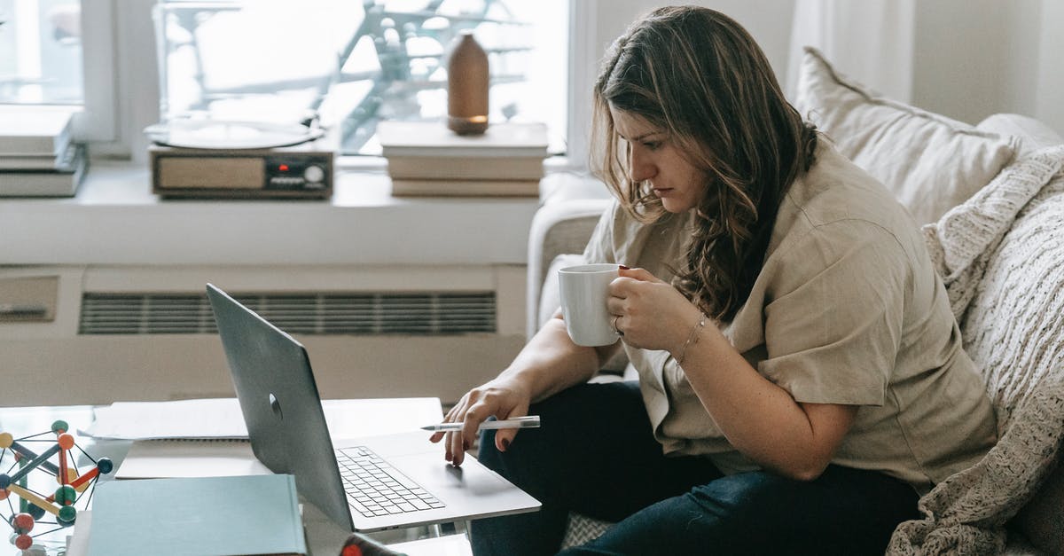 Brewing coffee concentrate using both hot and cold methods - Freezing concentrate - Woman with cup sitting on couch while working on laptop