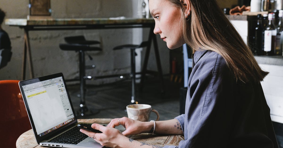 Brewing coffee concentrate using both hot and cold methods - Freezing concentrate - Side view of young focused woman browsing laptop sitting at table with cup of hot beverage in cafe