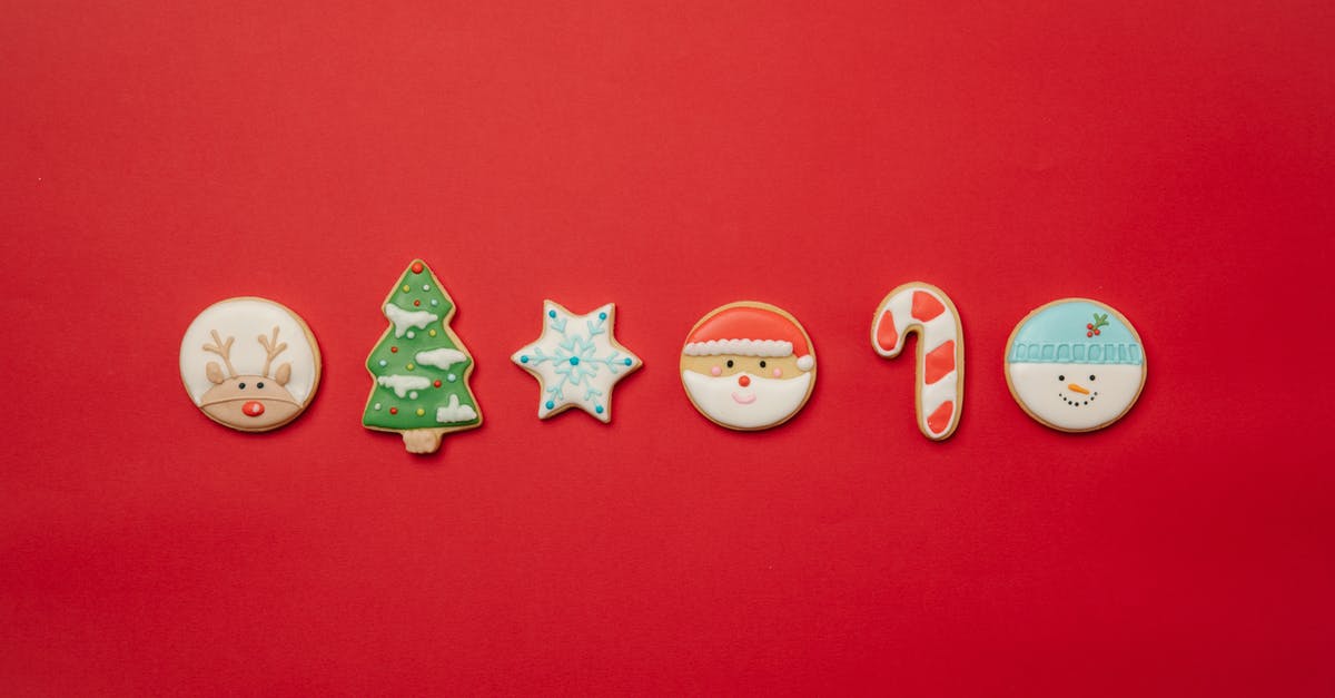 British equivalent for Cane sugar - Top view of assorted Christmas cookies of different shapes decorated with colorful icing and arranged in row on red background