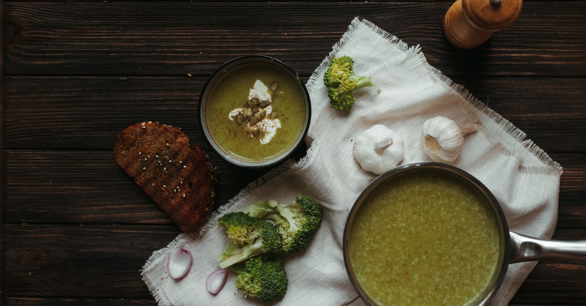 Broccoli Cheddar soup coming out pasty - Top view of saucepan with broccoli puree soup on white napkin with garlic and toasted bread slice