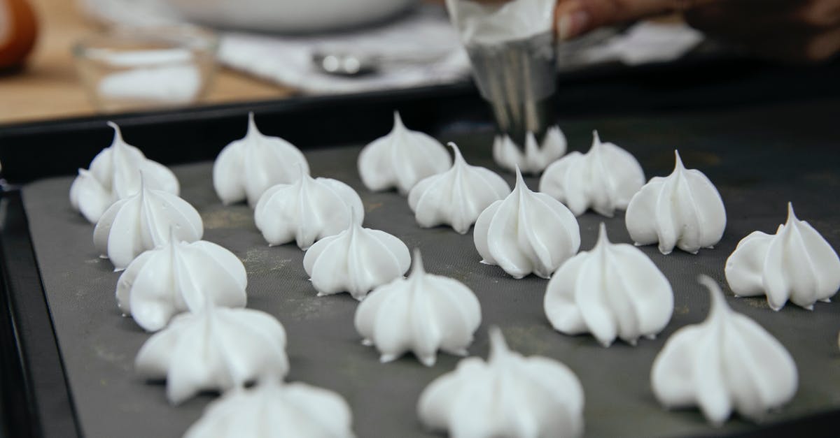 Broil meringue cookies? - Crop unrecognizable chef with piping bag with star tip forming vanilla meringue cookies on baking pan in kitchen