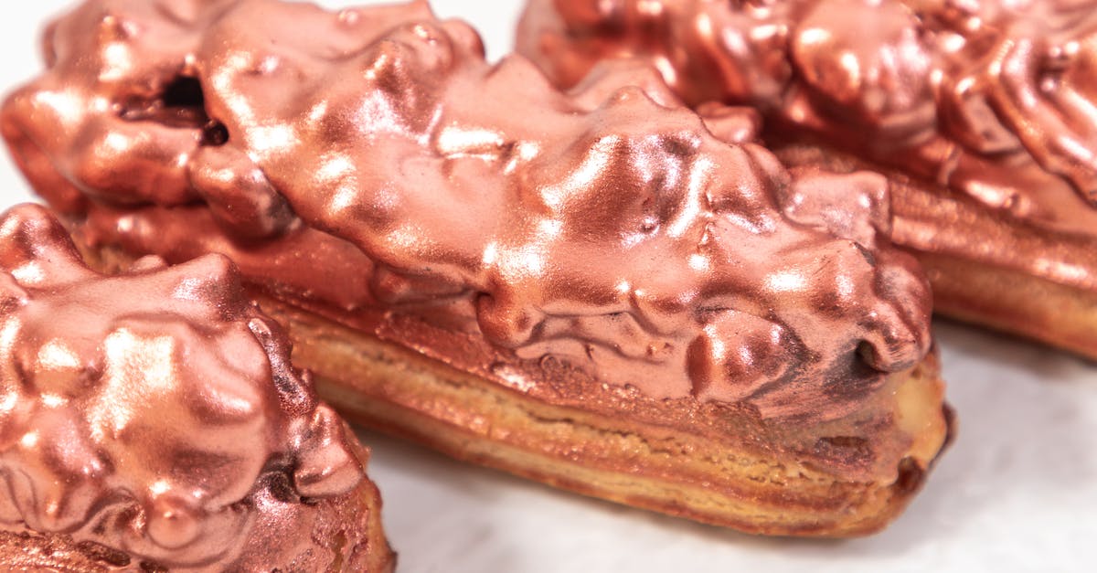 brothy baked beans [closed] - Closeup of served sweet eclair pastries with glaze under golden rose dust on plate