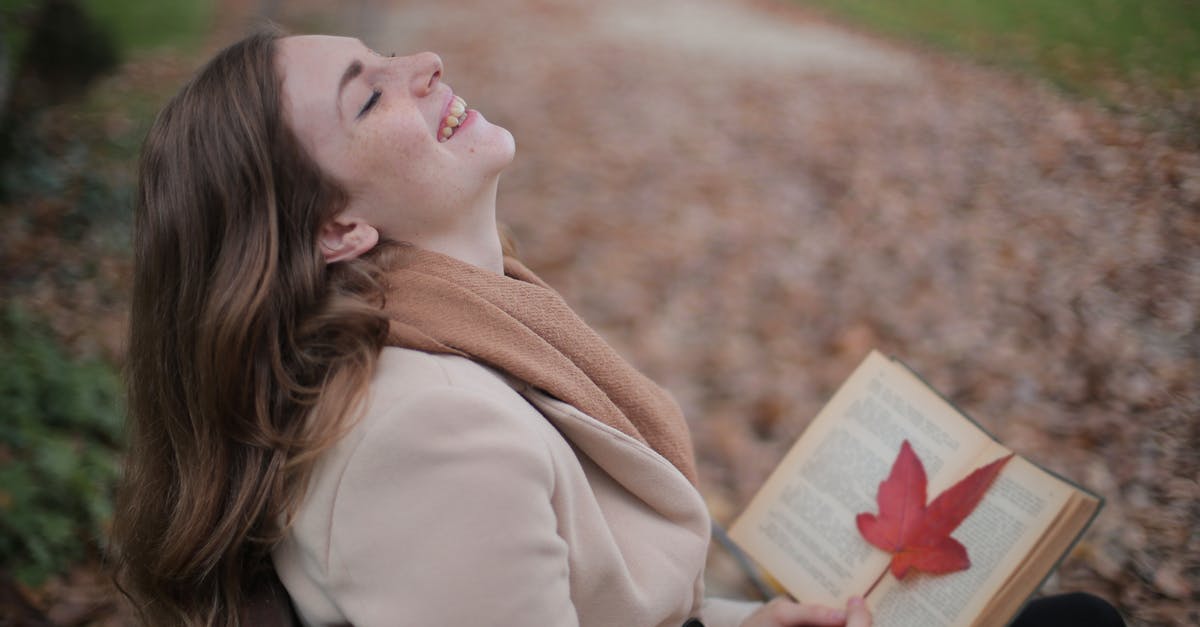 Brown Blob in natural maple syrup? - Cheerful young woman with red leaf enjoying life and weather while reading book in autumn park