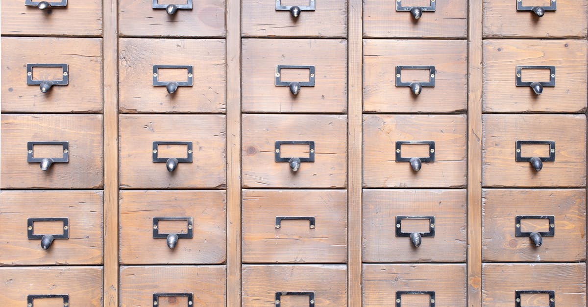 Brown line in back of shrimp - Background of wall full of many similar aged shabby vintage wooden drawers with metal round handles