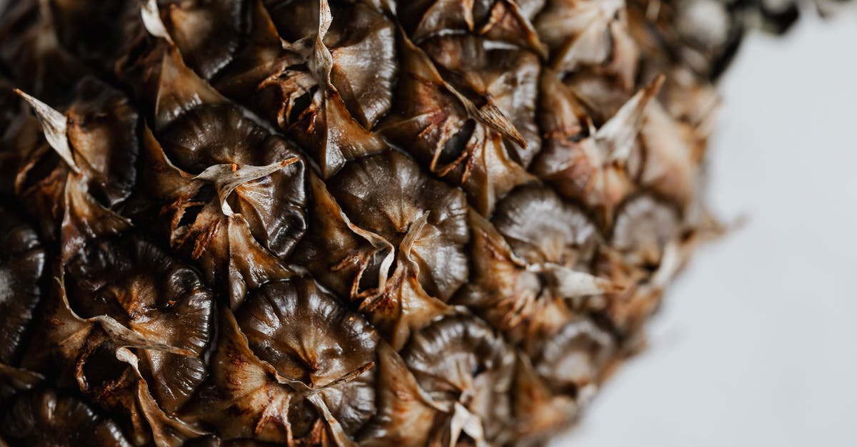 Brown pods from tree like Carob okay to eat raw? [closed] - Whole unpeeled pineapple on white background