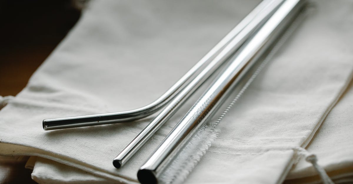 Brown spots on new stainless steel pot - Collection of stainless steel straight and bent straws placed on reusable bags on table