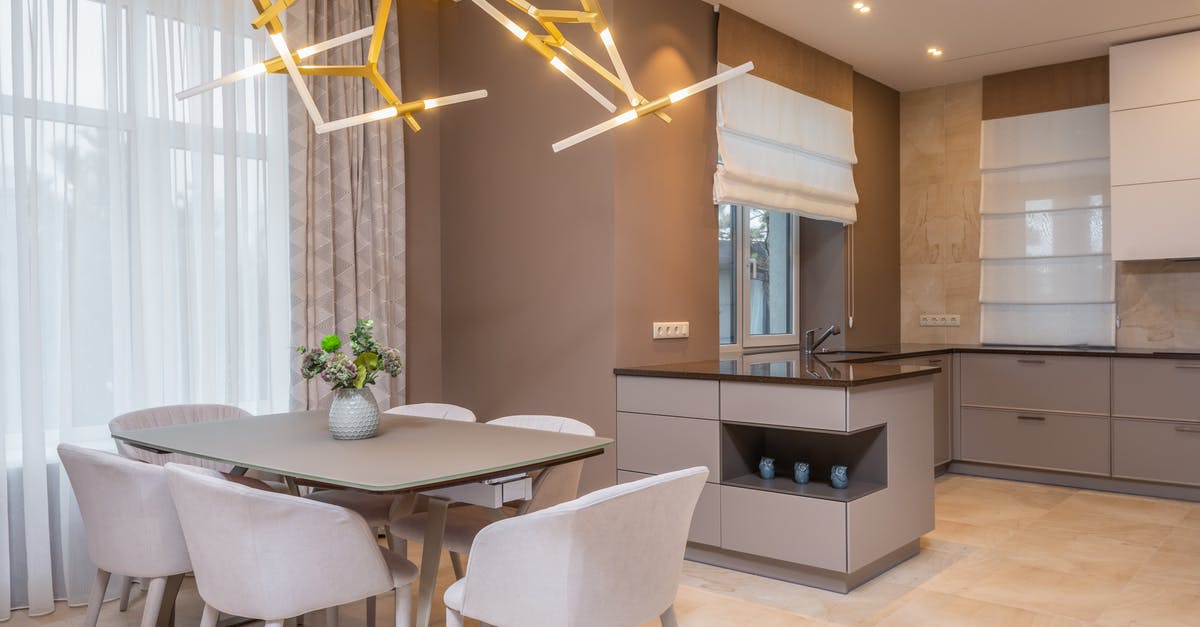 Brown spots on new stainless steel pot - Contemporary open plan kitchen with gray matte cabinets and dining table under contemporary geometric lamp in spacous apartment