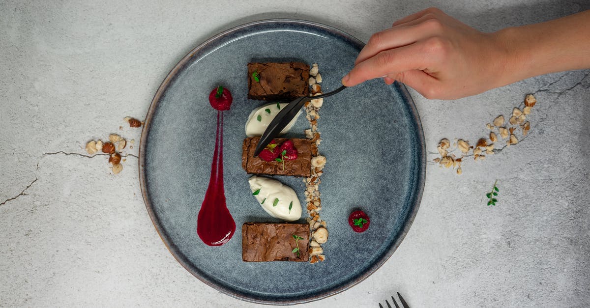 Brownie with chocolate mousse on top - Top view of crop anonymous person holding spoon while eating delicious chocolate dessert from ceramic plate