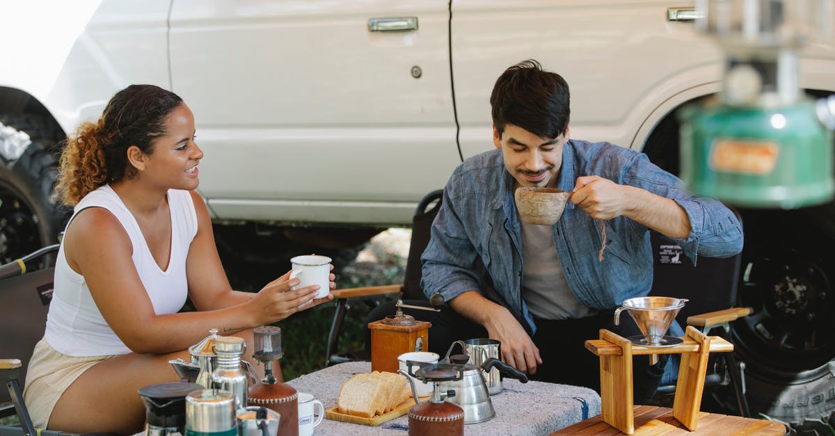 Caffeine content of cold-brewed coffee: higher or lower than hot-brewed? - Positive diverse couple drinking delicious pour over coffee in campsite