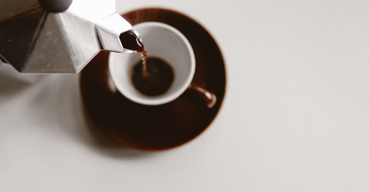 Caffettiera (Moka Pot) is not making coffee properly - From above of geyser coffee maker pouring freshly brewed beverage into ceramic cup placed on white table